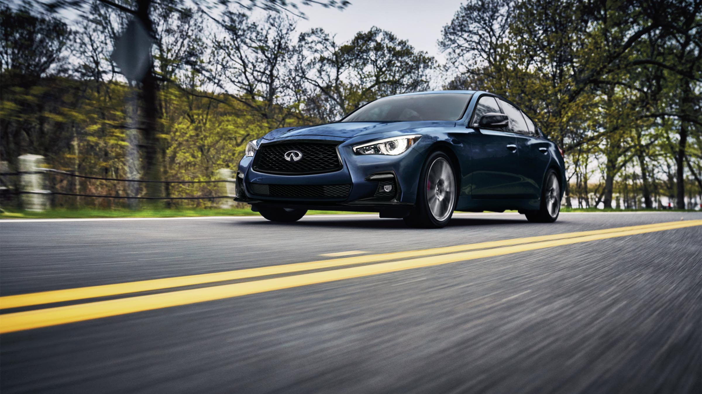 Exterior view of a blue 2022 INFINITI Q50 on the road.