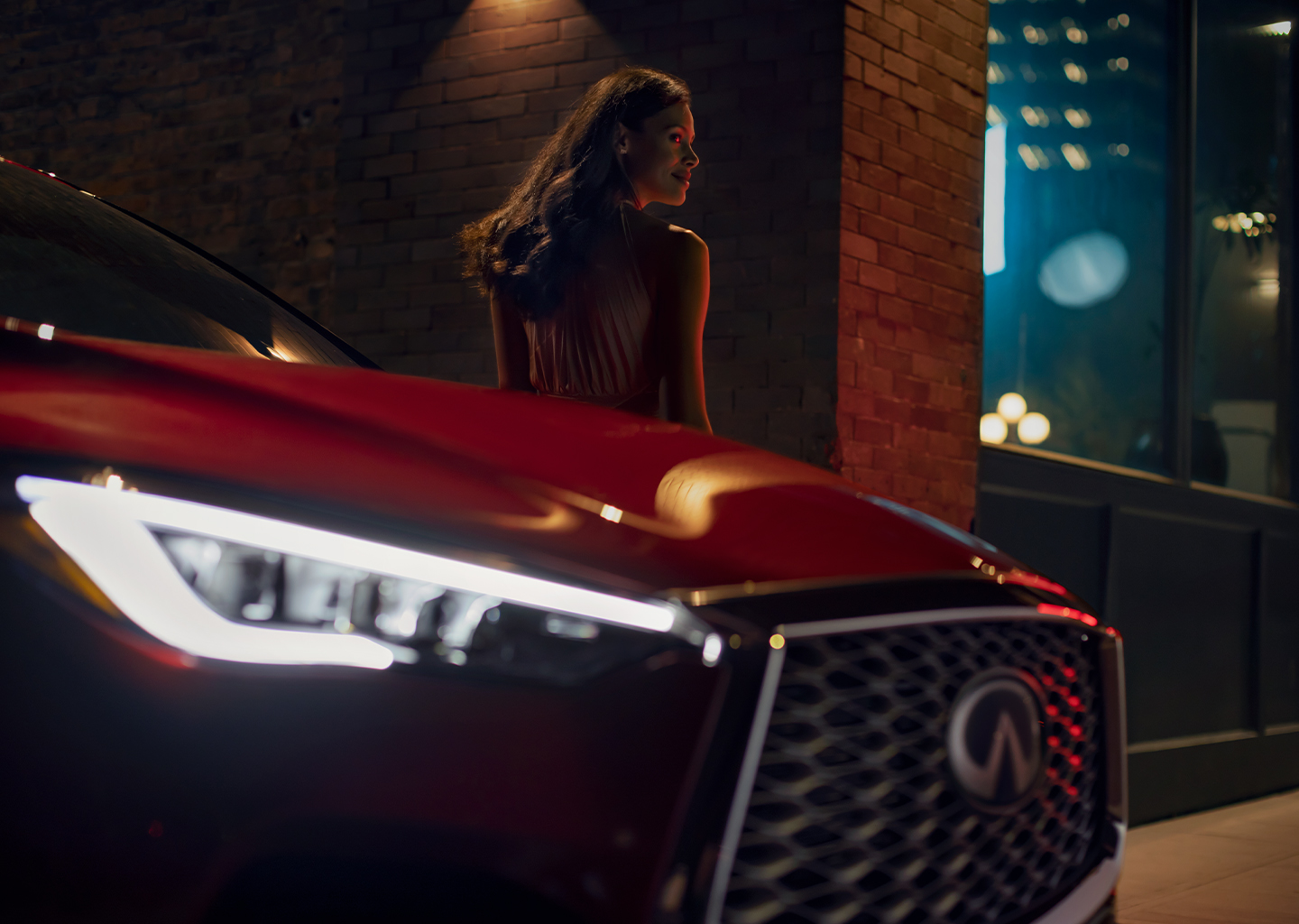Owner leaning against red INFINITI vehicle