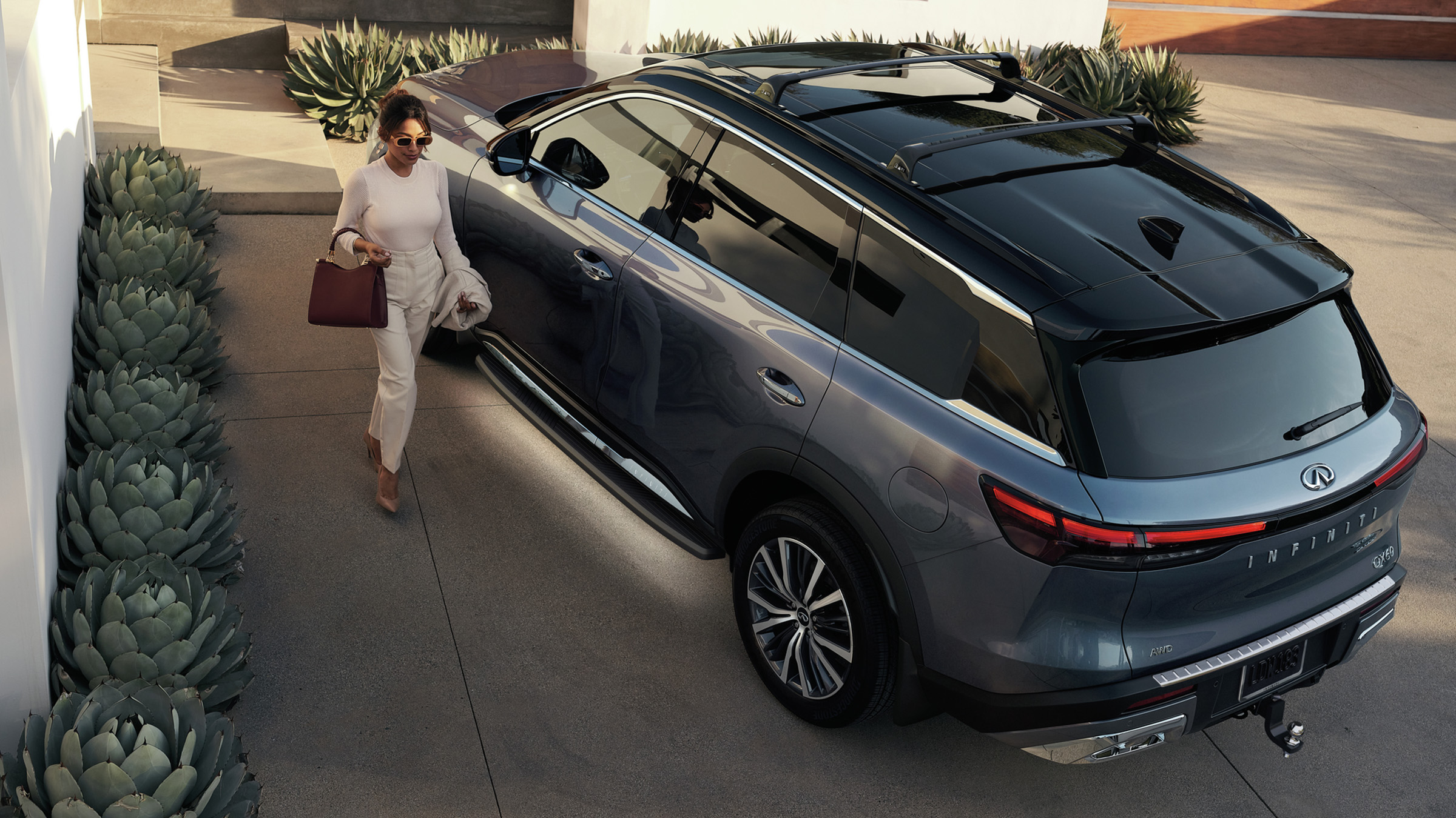 Bird's eye view of a woman walking away from her parked 2022 INFINITI suv.