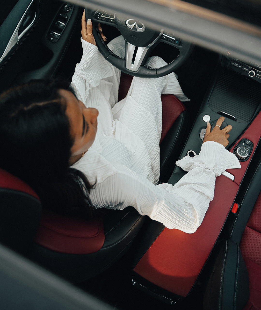Overhead view of a driver in the 2024 INFINITI QX55 crossover coupe with red and black interior