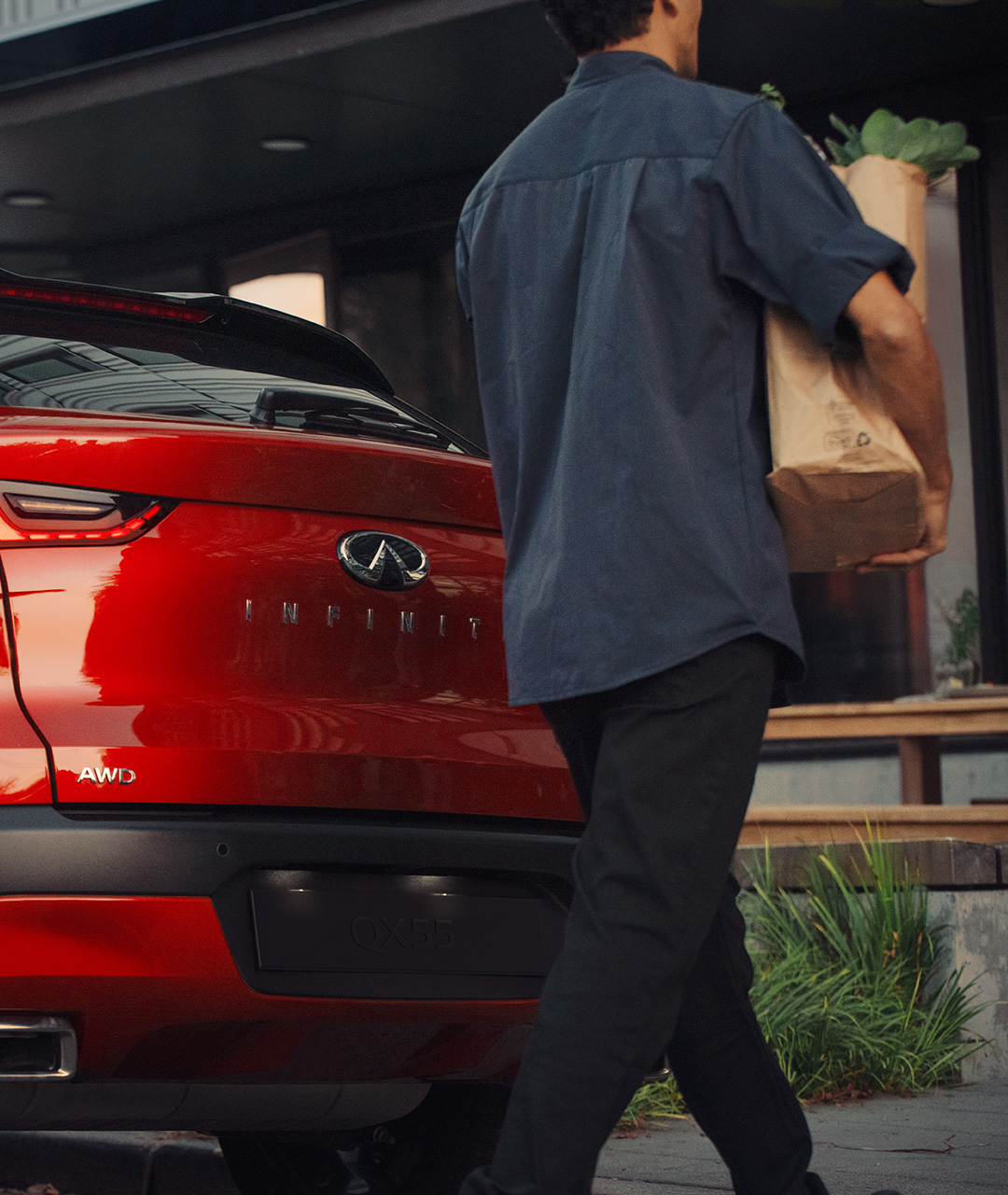 Owner of a red 2024 INFINITI QX55 crossover coupe walking with groceries