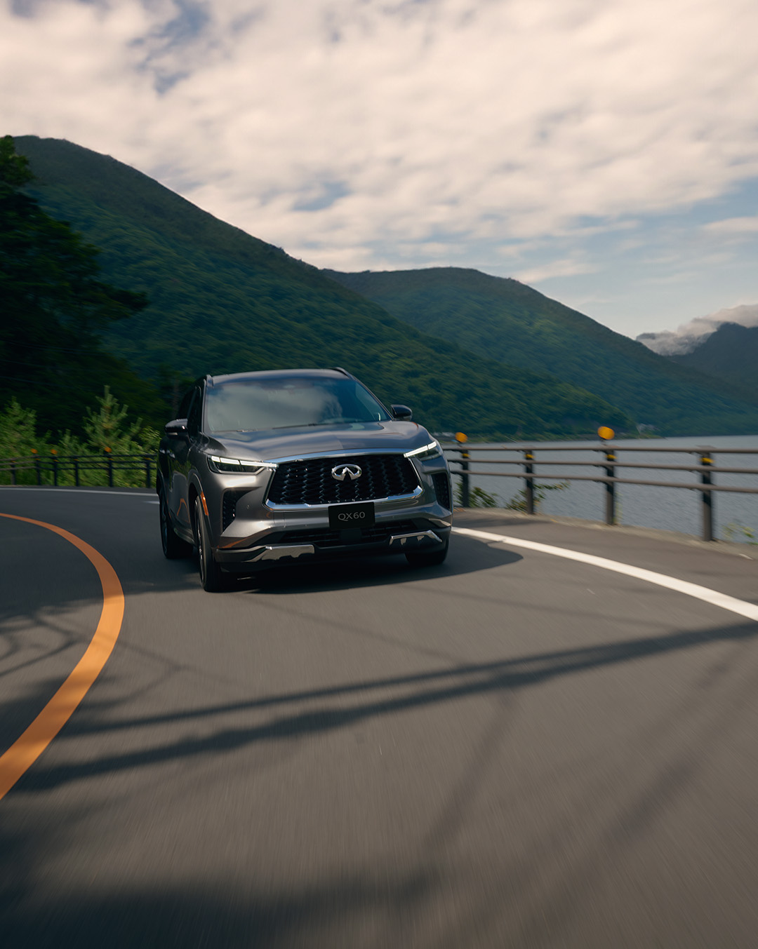 Front view of the 2024 INFINITI QX60 SUV driving on the road