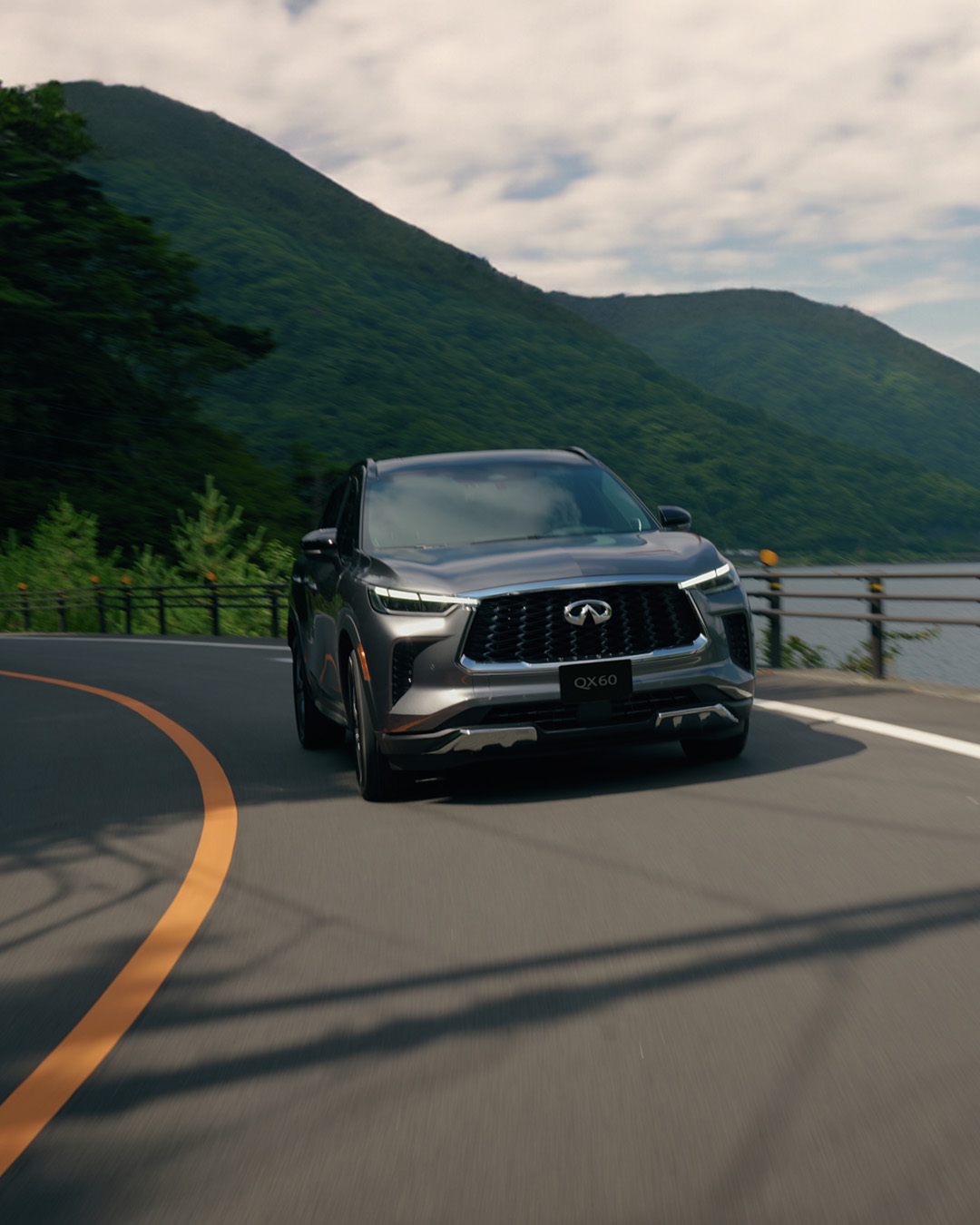 Front view of the 2024 INFINITI QX60 SUV driving on the road