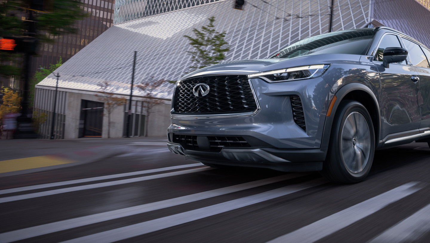 Close-up angled view of the 2024 INFINITI QX60 3-row SUV driving fast